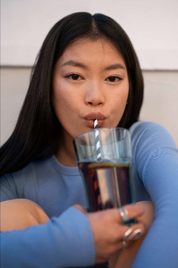 person-drinking-kombucha (1) 투명한 치아의 원인이 될 수 있는 탄산음료를 마시는 여성.