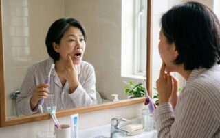 거울을 보며 오래된 어금니 금니를 살펴보는 여성