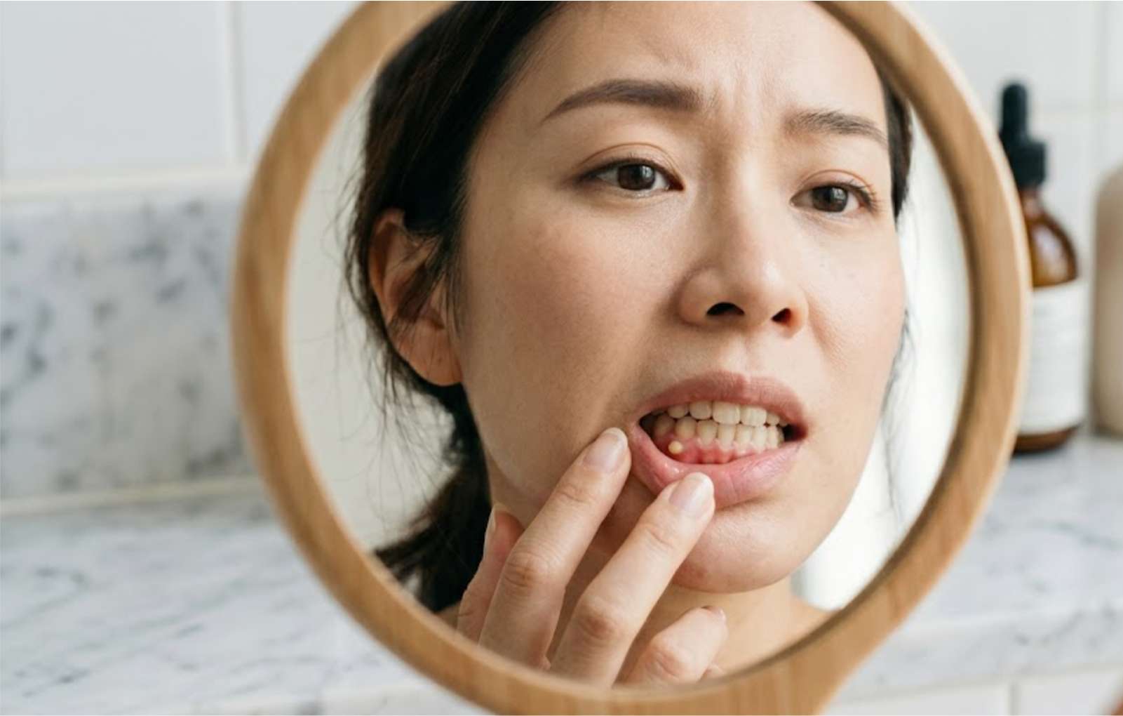 사무실에서 거울을 보며 잇몸 뾰루지를 확인하는 피곤한 직장인의 모습